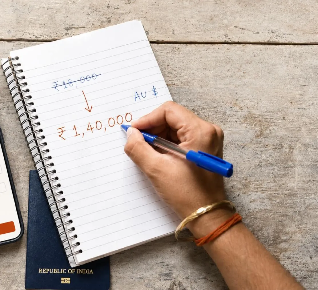 A hand crosses out ₹18,000 in a notebook and writes ₹1,40,000 below it, an Indian passport underneath