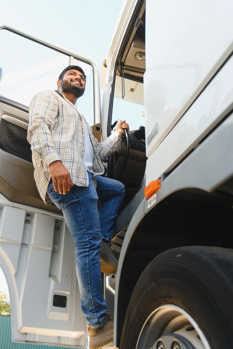 A driver steps up into the cab of a white semi truck