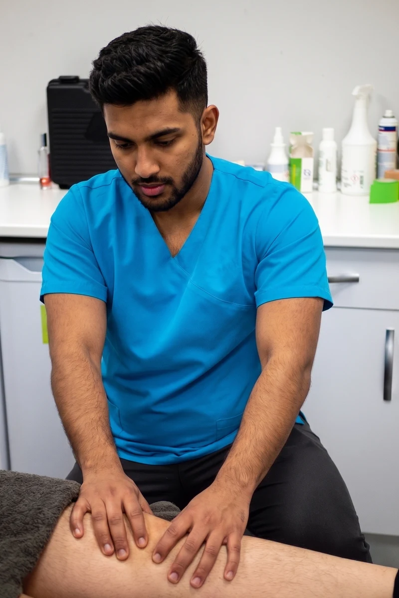 A physiotherapist works on a patient's knee on a treatment table in a clinic